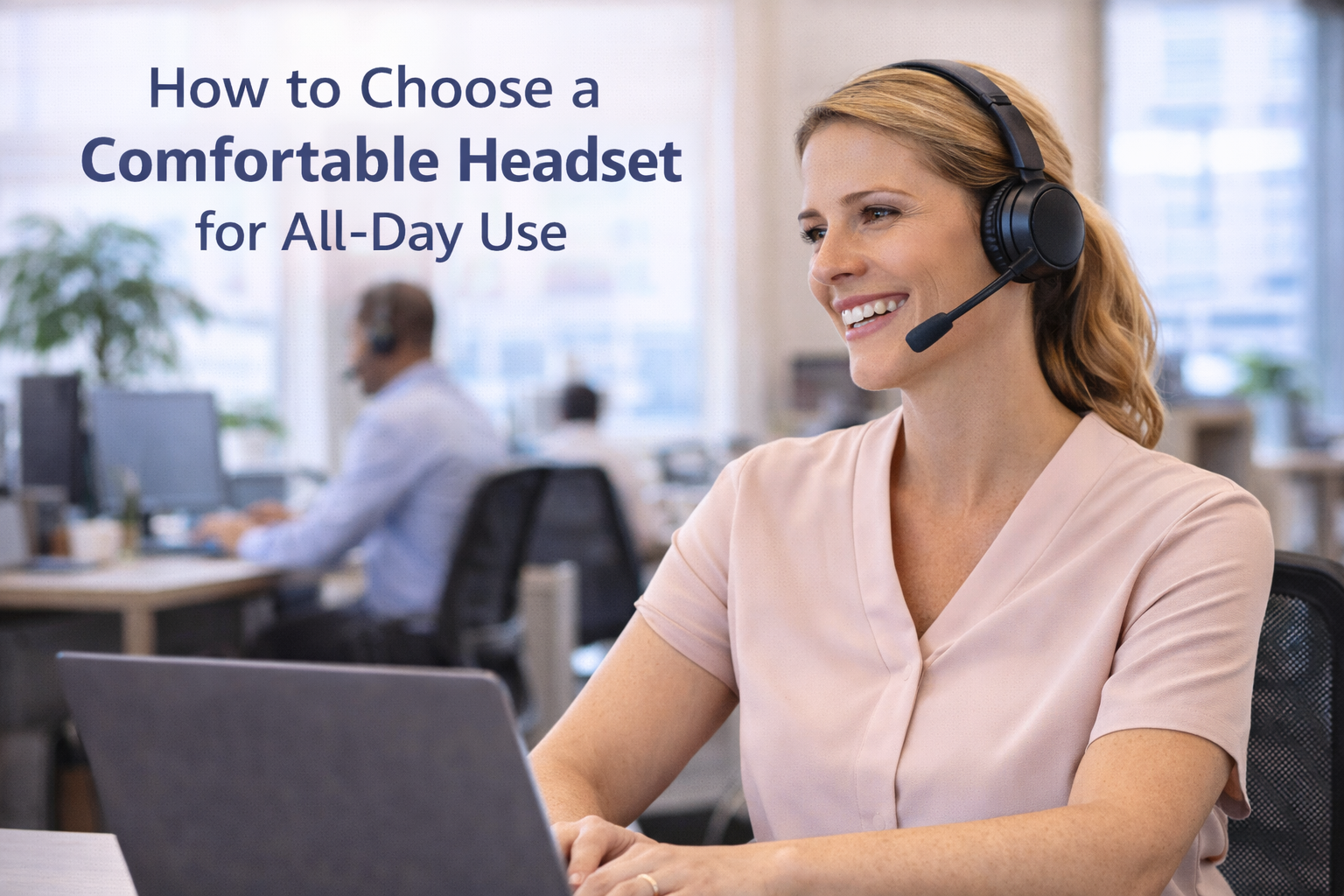 woman working in open office, at laptop smiling while on a call, wearing a headset